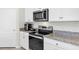 Modern kitchen features stainless steel appliances, granite countertops, and sleek white cabinetry at 493 Talisi Loop, St Cloud, FL 34771