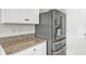 Close-up of granite countertops and stainless steel fridge with water dispenser in the modern kitchen at 493 Talisi Loop, St Cloud, FL 34771