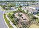 Aerial view of community playground with play equipment, landscaping, and black metal perimeter fencing at 493 Talisi Loop, St Cloud, FL 34771