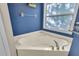 Corner bathtub with chrome hardware and fixtures with a window and navy blue walls at 5108 Legacy Oaks Dr, Orlando, FL 32839