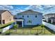 A fenced backyard features a screened porch, green grass and young palm trees at 5645 Camilla St, St Cloud, FL 34771