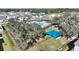 Aerial view of a community pool with shaded picnic area, lounge chairs, and green spaces amid lush landscaping and trees at 5645 Camilla St, St Cloud, FL 34771