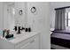 Bathroom featuring a white vanity with a modern black faucet and a glimpse into a bedroom with two beds at 6165 Carrier Dr # 3701, Orlando, FL 32819