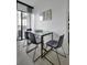 Bright dining area with a glass-top table, four gray chairs, and access to a balcony with natural light at 6165 Carrier Dr # 3701, Orlando, FL 32819
