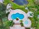 Aerial view of community pool with lounge chairs, landscaping, and a nearby pond at 619 Lake Marion Golf Resort, Kissimmee, FL 34759