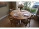 Dining area featuring a round wooden table set for four, with natural light streaming in from the window at 7465 Bleecker Ln, Kissimmee, FL 34747