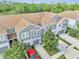 Aerial view shows three-story townhomes with neutral siding, tile roofs, and well-manicured lawns at 9161 Shepton St, Orlando, FL 32825