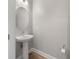 This half bathroom features a pedestal sink, oval mirror, and wood-look floors at 936 Wild Date Ln, Lake Mary, FL 32746