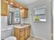 Bright bathroom features a framed mirror, wooden cabinetry, and a window for natural light at 14772 Eagles Crossing Dr, Orlando, FL 32837