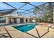 View of a large pool and screened-in patio with a lake view in the distance at 14772 Eagles Crossing Dr, Orlando, FL 32837