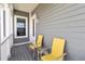 Cozy front porch with gray siding, two yellow chairs, and a small table at 1552 Fairview Cir, Reunion, FL 34747