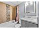 Modern bathroom with decorative tiles in the shower and a vanity with gray cabinets and a large mirror at 1716 2Nd Ne St, Winter Haven, FL 33881