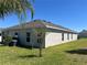 The backyard has a view of lush lawn and a tree for shade with an AC unit on the side of the home at 179 Blue Cypress Dr, Davenport, FL 33837