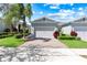 Charming home featuring a well-manicured lawn and a two-car garage, set under a sunny sky with beautiful landscaping at 1830 Estuary Ln, Kissimmee, FL 34747