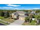 Well-maintained home featuring a three-car garage, stone veneer, manicured lawn, and lush plantings under a blue sky at 2015 Sandy Garden Ln, Winter Garden, FL 34787