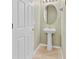 Powder room featuring a pedestal sink, oval mirror, and white door at 2040 Retreat View Cir, Sanford, FL 32771