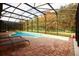 Screened-in pool with brick patio, chaise lounges, and an outdoor view of the surrounding trees and blue skies at 2788 Roccella Ct, Kissimmee, FL 34747