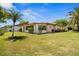 Well-manicured backyard with lush green lawn, mature trees, and the exterior of the home at 398 Troon Ct, Winter Haven, FL 33884