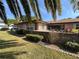 Brick home backyard featuring a beautiful courtyard, flowerbeds, and mature trees at 398 Troon Ct, Winter Haven, FL 33884