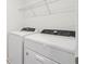 A laundry room with a newer white washer and dryer with wire rack shelving above at 4337 Switchgrass Ln, St Cloud, FL 34772