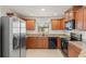 Kitchen with stainless steel refrigerator, granite countertops, brown cabinets, and modern appliances at 517 Delta Ave, Groveland, FL 34736