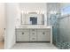 Modern bathroom features a double vanity, framed mirror, and glass-enclosed shower with decorative tile accents at 8006 Hoylake Dr, Orlando, FL 32832