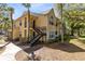 Bright yellow condo featuring black metal stairs, palm trees, and a sidewalk leading to a well-maintained community at 1017 S Hiawassee Rd # 3718, Orlando, FL 32835