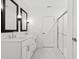 Bathroom featuring a double vanity, framed mirrors, and a glass-enclosed shower with marble flooring at 13405 Sw 88Th Ter # 53, Ocala, FL 34473