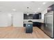 Bright, open kitchen with stainless steel appliances, dark cabinets, island, and wood-look tile flooring at 13405 Sw 88Th Ter # 53, Ocala, FL 34473