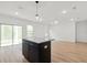 Open concept living space with kitchen island, sliding doors, wood-look tile flooring, and modern lighting at 13405 Sw 88Th Ter # 53, Ocala, FL 34473