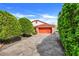 Home featuring lovely manicured shrubbery leading up to a bright red garage door at 13542 Texas Woods Cir, Orlando, FL 32824