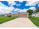 Inviting single-story home features a long driveway and attached two-car garage, under a bright blue sky at 142 Barrington Dr, Kissimmee, FL 34758