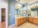 Bathroom with double vanities, framed mirrors, and linen shelving at 14228 Portrush Dr, Orlando, FL 32828