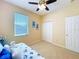 Cozy bedroom features a ceiling fan, window with blinds, and carpeted floors at 14228 Portrush Dr, Orlando, FL 32828