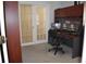 Functional home office space with built-in desk, storage, three monitors, and glass paneled doors to another room at 1457 Waukon Cir, Casselberry, FL 32707