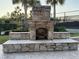 Detailed stone outdoor fireplace feature with integrated seating and classic arch design at 14675 Scott Key Dr, Winter Garden, FL 34787