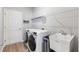 Well-lit laundry room with modern washer and dryer, utility sink, and storage shelves at 149 St Thomas Dr, Mulberry, FL 33860