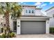 A modern two-story home featuring decorative stone, well-manicured landscaping, and a gray garage door at 1523 Corolla Ct, Reunion, FL 34747