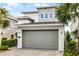 A modern home featuring a gray garage door, stone accents, and lush landscaping at 1523 Corolla Ct, Reunion, FL 34747