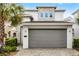 Two-story home with a gray two-car garage and decorative stone facade accents at 1523 Corolla Ct, Reunion, FL 34747