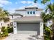 A contemporary-style home with a gray garage door, stone accents, and a lushly landscaped yard at 1523 Corolla Ct, Reunion, FL 34747