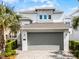 A modern home showcasing a gray garage door and lush landscaping against a blue sky at 1523 Corolla Ct, Reunion, FL 34747
