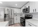 Modern kitchen featuring stainless steel appliances and white cabinets with stylish black hardware at 1563 Immocalee St, Intercession City, FL 33848