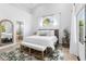 Bright bedroom with wood bed frame, bench, and arched window, leading to the bathroom at 1667 Spring Loop Way, Winter Garden, FL 34787