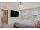 Bedroom featuring neutral carpet, a bed with gray bedding, a TV, and two windows at 2736 Dumont Ln, Tavares, FL 32778