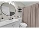 Modern bathroom features a round mirror, stylish shelving, and a shower with a neutral-toned curtain at 295 Garland St, Deltona, FL 32725