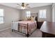 Comfortable bedroom with a ceiling fan, two windows, and a decorative black metal bed frame at 31807 Broadwater Ave, Leesburg, FL 34748