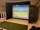 Indoor golf simulator with a large screen display and golf equipment in the room at 334 Prestwick Dr, Davenport, FL 33897