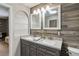 Bathroom with dual sinks, granite countertops, framed mirrors, and wood-look accent wall at 9939 Triple Crown Cir, Orlando, FL 32825