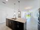Kitchen island open to living area with pendant lights, stainless steel dishwasher, and tile flooring at 10018 Halesia Woods Dr, Orlando, FL 32832